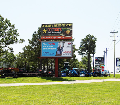 2 stacked billboards in front if Hirsh Farm Store with tractors out front